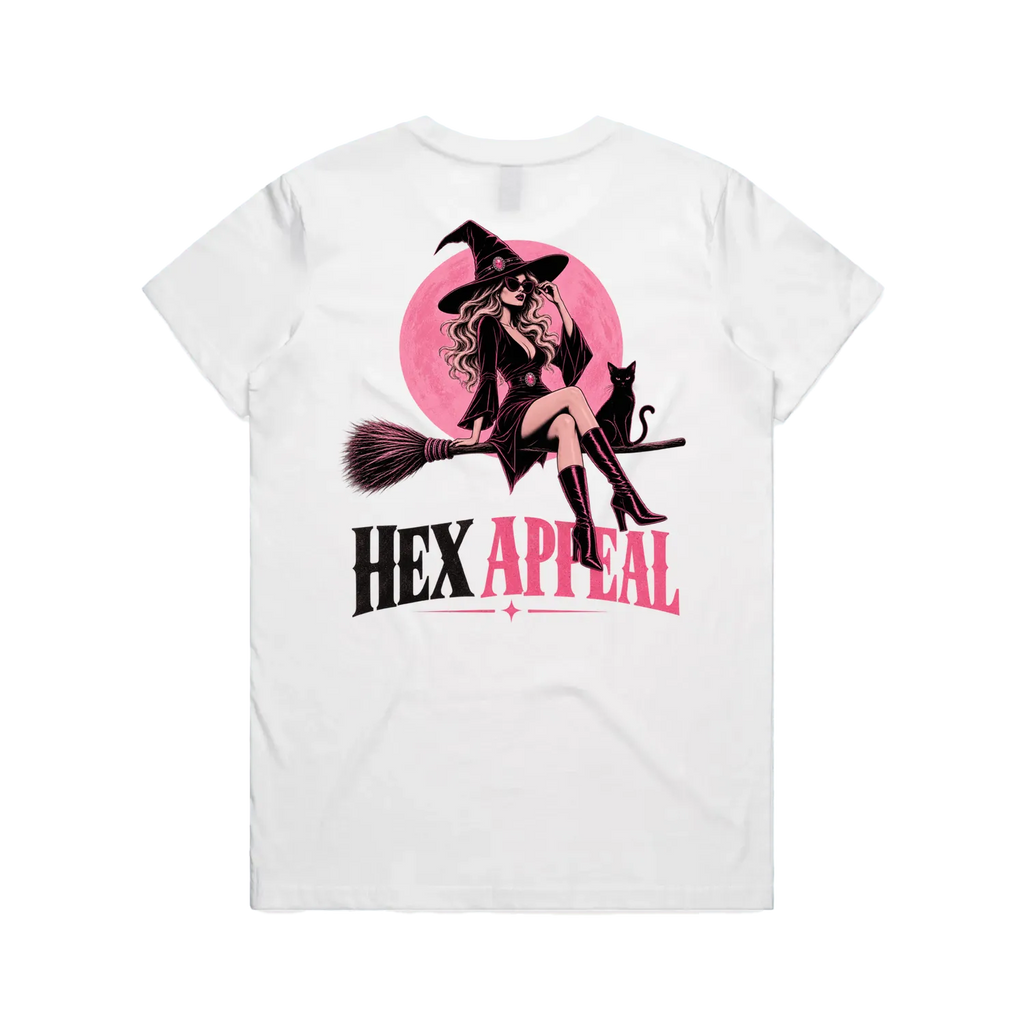 A white short-sleeve t-shirt shown from the back, featuring a large graphic print of a witch sitting on a broomstick in front of a pink circle, with the text 'HEX APPEAL' printed below in black and pink.